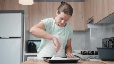 Dişi pasta şefi kremayı yavaşça kaşık kullanarak pişirme çarşafına serer..