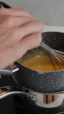 Kadın tencerenin içindekileri yavaş çekimde buharda çırparak karıştırıyor. Dikey video.