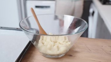 Kamera, içinde krema olan cam kaseye bakıyor..