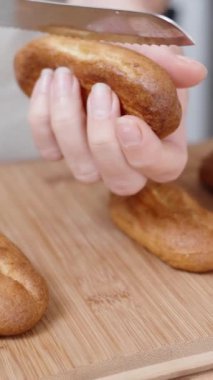Dişi pastacı onları doldurmak için ekleri yavaş çekimde ikiye böler. Dikey video.