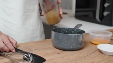 Kadın tencereye nektarin püresi döküyor..