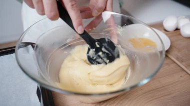 Kadın hamuru şeffaf bir cam kaseyle siyah bir spatulayla karıştırıyor, ağır çekimde..