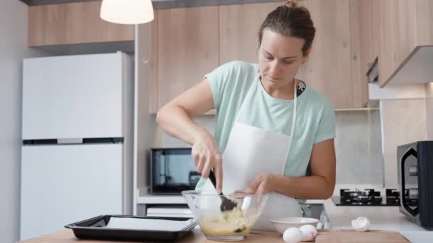 在明亮的厨房里 一个年轻的女人正在用慢动作的铲子搅拌着巧克力糕点 — 图库视频影像