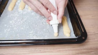 Kadın eklerleri hazırlıyor. Choux 'nun pastasını yakın plan çekimde bir yemek tepsisine koyuyor..