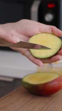Bir kadın yakınlarda çilek ve nane ile mango küp küp kesiyor. Ağır çekim. Dikey video.