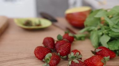 Çilek dolgulu ev yapımı ekler, mango dilimleri ve beyaz bir mutfağın arka planına karşı ahşap bir masada nane şekeri..