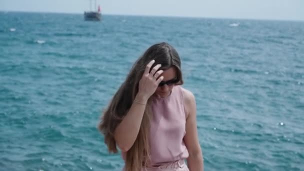 一个年轻的女人在大海和小船的背景下走向我 她的长发在风中摇曳 慢动作 — 图库视频影像