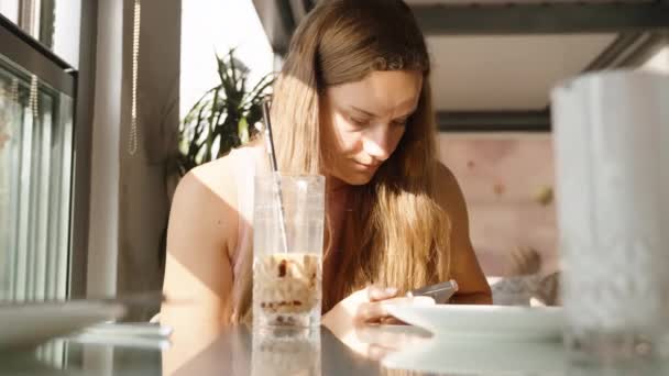 Ung Kvinne Kafé Ser Smarttelefonen Med Uferdig Cocktail Tallerkener Bordet – stockvideo