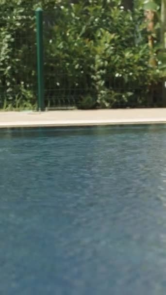 Uitzicht Het Blauwe Water Van Het Zwembad Een Witte Ligstoel — Stockvideo