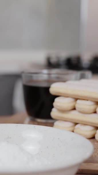 여자가 크림을 채찍질하는 티라미수 케이크의 재료는 테이블에 있습니다 비디오 — 비디오