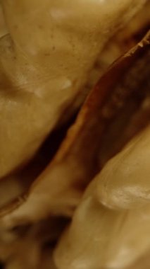 Düşme konseptini sembolize eden, siyah arka planda dönen yarım soyulmuş bir ceviz. Makro atış, izole edilmiş. Dikey video.