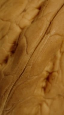 Bir ceviz döner ve aşağı doğru siyah bir zemine düşer. Makro atış, izole edilmiş. Üst Manzara. Dikey video.