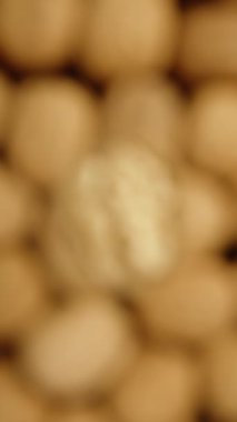 Görüntü konsepti odaklı olmayan bir çekim. Kamera yavaşça ters perspektiften çekilmiş kısmen soyulmuş bir cevize odaklanıyor. Dikey video.