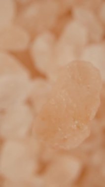Küçük pembe bir deniz tuzu tanesi tuz kümesinin üzerine düşüyor, makro zoom, yukarıdan aşağı görüş. Dikey video.