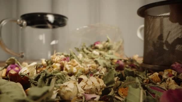 テーブルに散らばった花と茶葉のミックス 私は彼らの一部を醸造のふるいに置きました — ストック動画