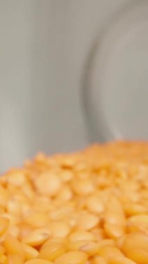 Camdan bir mercimek kavanozu masaya düştü ve sallanırken kamera makro görüntüde içeriden zumluyor. Dikey video.