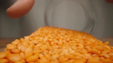 Kamera kırmızı mercimek kavanozunun içinden fırlıyor ve ben onları yavaşça masaya döküyorum..