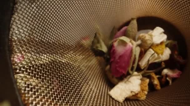 宏观变焦镜头 茶水里放着洋甘菊花和玫瑰花瓣的相机 我把它放进茶壶里 — 图库视频影像