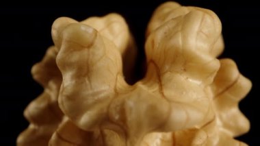 Kabuğu soyulmuş bir ceviz siyah arka planda uçar, makro kaydırıcı. İzole edilmiş.