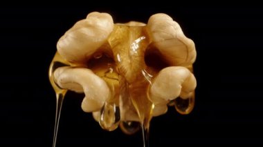 İçinden bal damlayan bir cevizin alttaki görüntüsü. Siyah bir arkaplanda izole edilmiş.