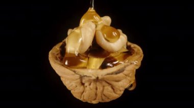 Kısmen kabuklu ceviz, içinden bal akıyor. Siyah arka planda yakın çekim..