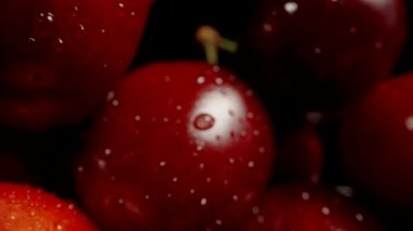 Masanın üzerinde, siyah bir arkaplana karşı büyük bir kiraz bolluğu. Dolly kaydırıcı aşırı yakın çekim.