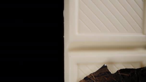 Napůl Rozbalená Bílá Čokoládová Tyčinka Otáčí Černém Pozadí Kamera Přiblíží — Stock video