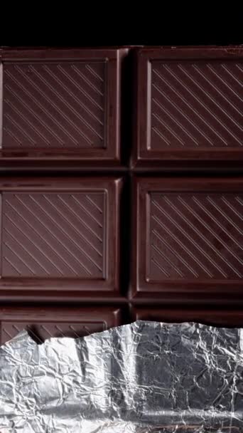 Dark Chocolate Bar Partially Wrapped Shiny Foil Spins Black Background — Stock Video