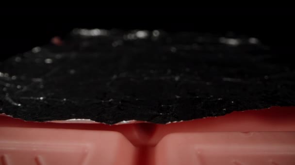 Een Roze Chocoladereep Gedeeltelijk Uitgepakt Van Folie Een Zwarte Achtergrond — Stockvideo
