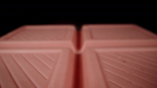 粉色巧克力棒似乎悬浮在黑色的背景上 孤立无援多利滑翔机极端特写 — 图库视频影像