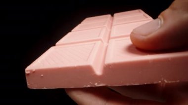 Elimde tutuyorum ve siyah arkaplandaki büyük pembe çikolatayı yakından inceliyorum..