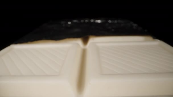 Ein Weißer Schokoriegel Teilweise Aus Der Folie Ausgepackt Auf Schwarzem — Stockvideo