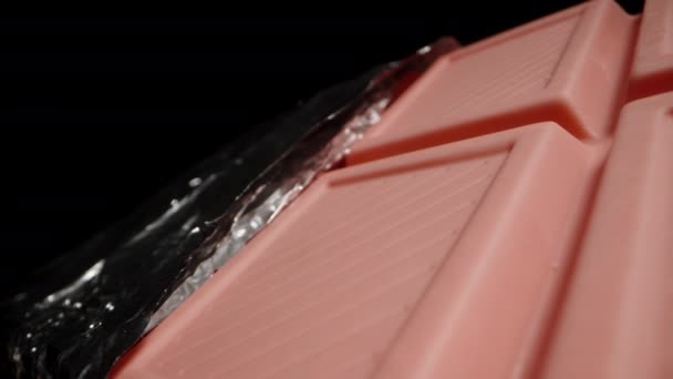 Large Pink Chocolate Bar Partially Unwrapped Foil Appears Falling Darkness — Stock Video