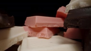 Masadaki pembe çikolatalar, siyah beyaz çikolataların yanında. Dolly kaydırıcı aşırı yakın çekim.