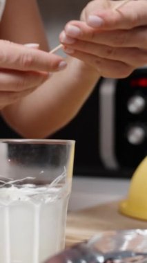 Kadın çilekleri beyaz çikolataya daldırdı ve onlara hindistan cevizi gevreği serpti. Dikey video.