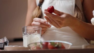 Beyaz önlüklü kadın çikolataya batırırken çilekleri çubuğa geçirir. Manzara aşağıdan..