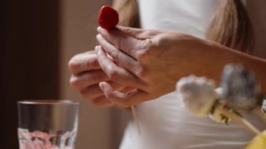 Kadın çilekleri çikolatayla hazırlıyor ve dekore ediyor. Arka planda hazır çilekler var..