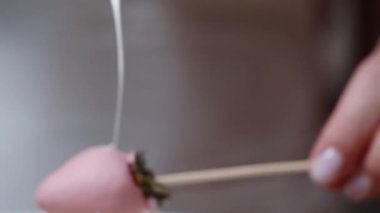 Ağır çekimde, beyaz çikolata süsleme için pembe çikolatayla kaplı çileğe uygulanıyor..
