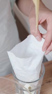Pasta şefi pastayı bir torbaya koyar ve kamera yavaşça yukarı doğru hareket eder. Dikey video.