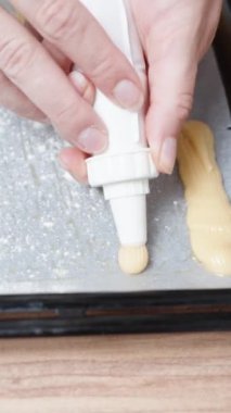 Kadın eklerleri hazırlıyor. Koux pastasını yakın plan çekimde bir yemek tepsisinin üzerine koyuyor. Dikey video.