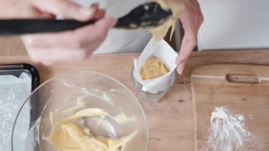 Yukarıdan bakıldığında, kadın pasta şefinin boru torbasını choux hamur işiyle doldurduğunu görüyoruz..
