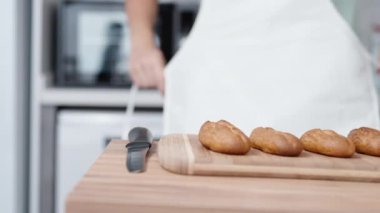 Ahşap masanın üzerinde, arka planda bir pastacı beyaz önlük giyerken ekinler var. Yanlarında çilek ve mango var..