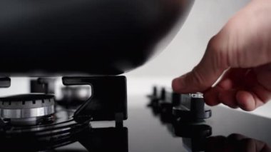 Yakın çekim panoramik manzara siyah ocağın üzerindeki gaz ocağının üzerinde büyük bir tencere ile tutuştuğunu gösteriyor..