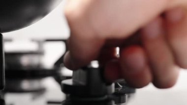 Yavaş çekimde, gaz sobasının düğmesini çeviriyorum ve tavayı ısıtmak için ocağı yakıyorum..