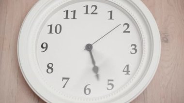 Ahşap bir duvardaki büyük beyaz saatler, hızla ilerliyorlar. Zamanlamalar