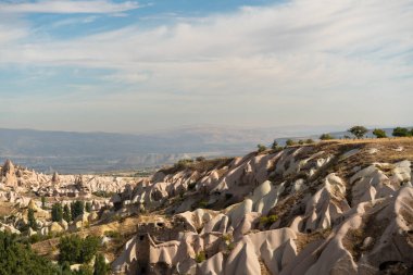 Cappadocia 'daki antik kayalar, kayalara oyulmuş eski oluşumlardan oluşan yüksek bir dağ manzarası ve evler..