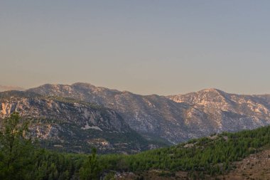 Güneşin son ışınları dağları seyrek çalılarla aydınlatıyor..