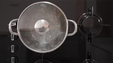 Kendimi yanıklardan korumak için kırmızı fırın eldiveni kullanarak tencerenin kapağını kaynar suyla kaldırıyorum. Manzara yukarıdan ve sahne yavaş çekimde..