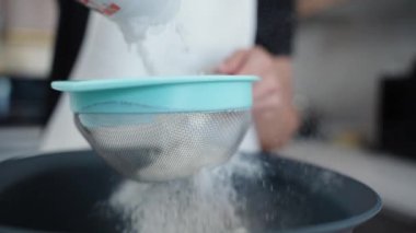 Bir kadın yavaş çekimde süzmek için eleğe un döküyor..