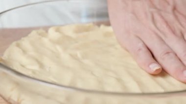Bir kadın hamuru eşit bir şekilde pişirme kabına yaymak için ellerini kullanır..